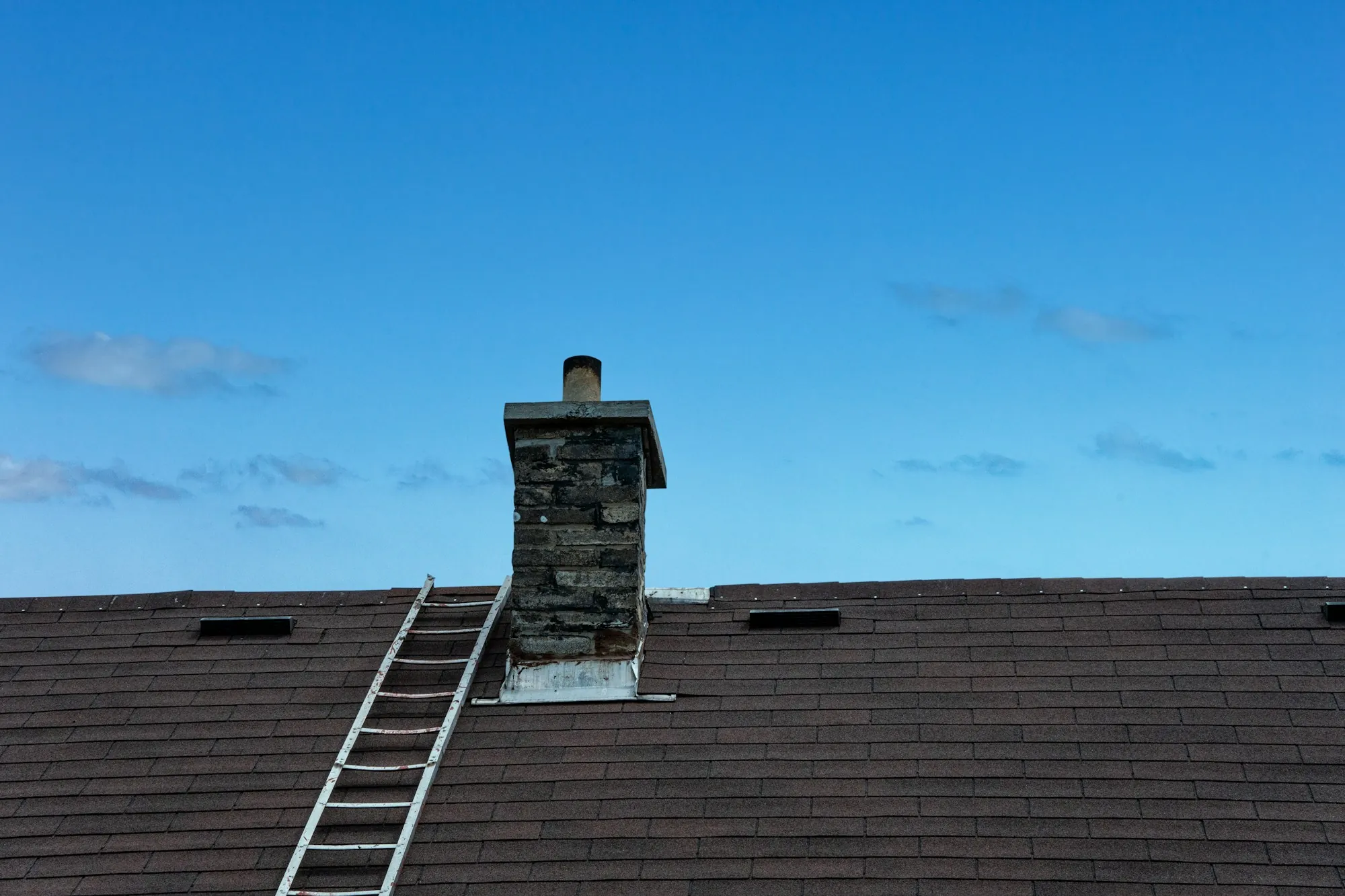 Ladder resting against a dark asphalt shingle roof, the starting point of a roof inspection in Berkeley Lake